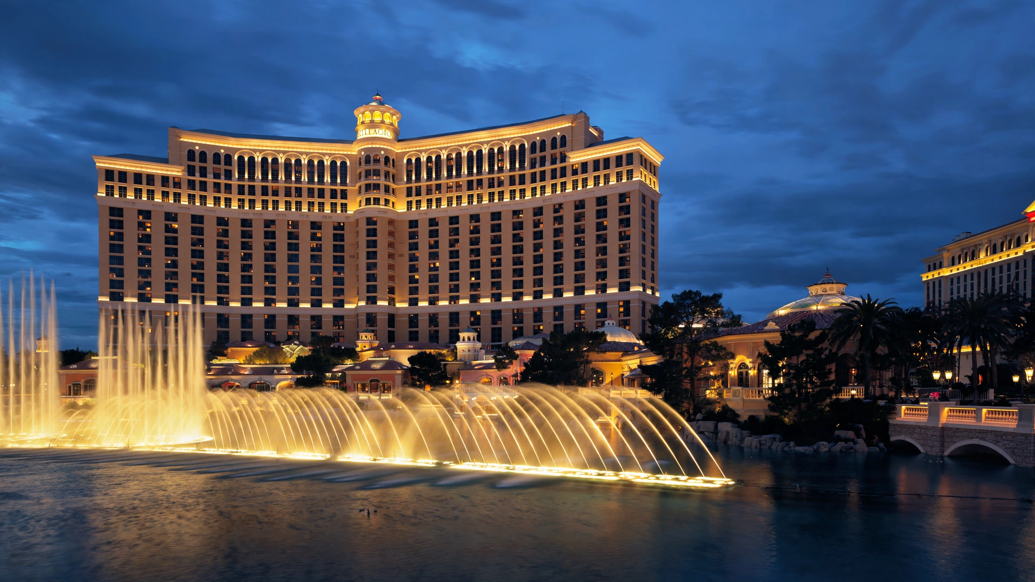 Evening exterior view of illuminated luxury casino hotel resort and grand fountains